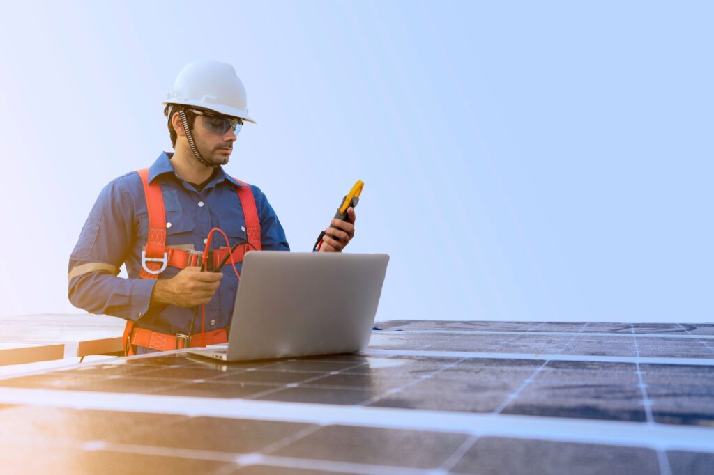 Male engineer using laptop to inspect solar panels